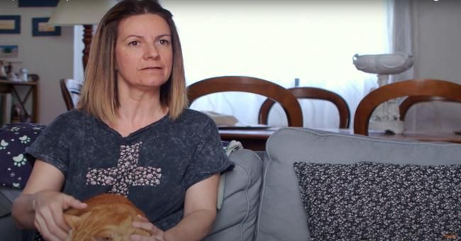 Mujer sentada en un sofá con un gato en su regazo.