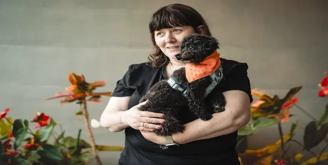 Personne agenouillée caressant un chien brun et blanc.